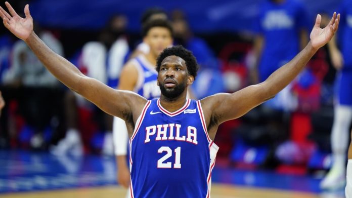 76ers star Joel Embiid celebrating with outspread arms.