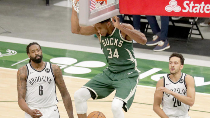 Giannis slam-dunking on the Brooklyn Nets defensive players.