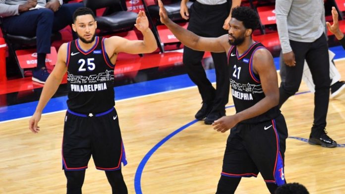 76ers players high-fiving on the hardwood.