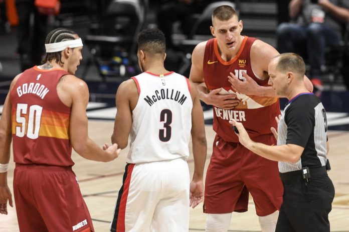 Nikola Jokic and other players contending a ref's call on the court.