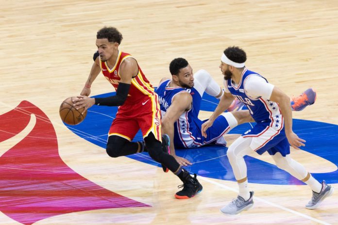 Trae Young running down court passed 76ers players.