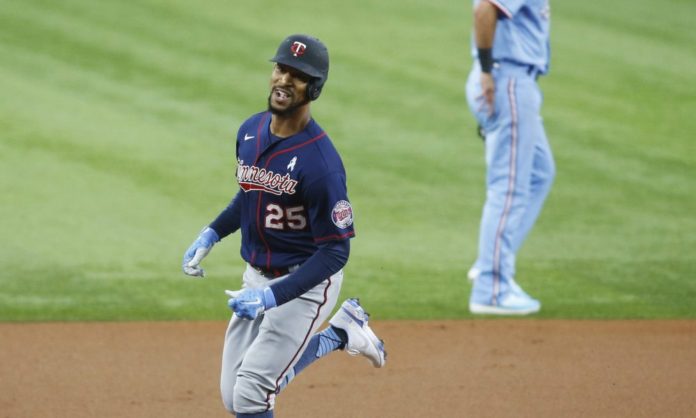 A Twins base runner after a big hit, smiling as he rounds the dirt.