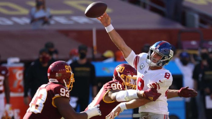 Giants QB Daniel Jones getting sacked while he tries to throw the ball.